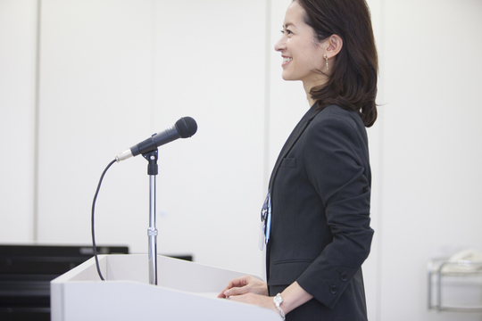 演台で司会する女性の写真
